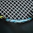 A close-up view of a tennis racket featuring a mesh pattern of white strings against a dark background. The rim of the racket is visible with blue, black, and yellow accents, and the text 'ENGINEERED POWER' is prominently displayed on the frame.